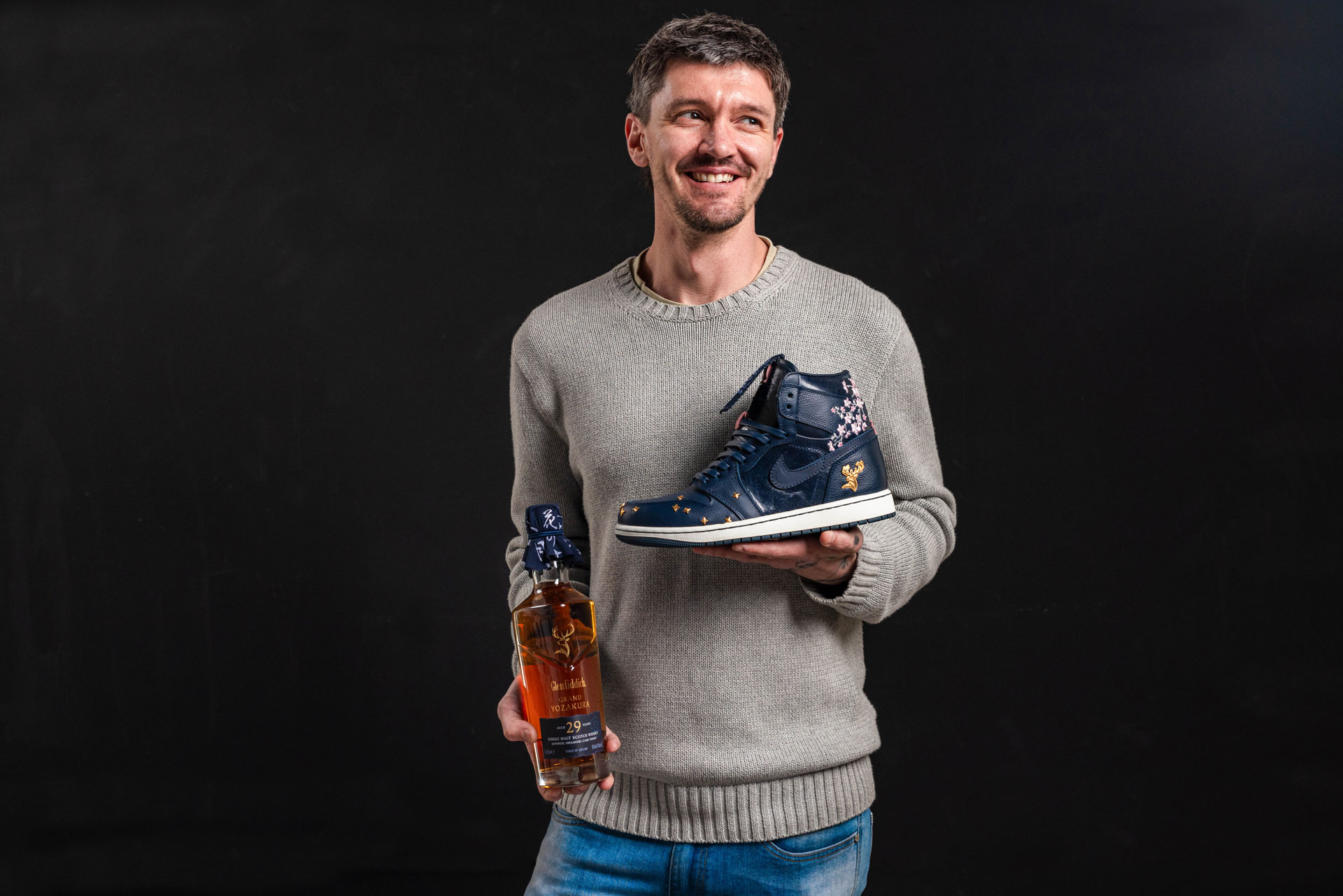 Chase Shiel holding custom sneakers and a bottle of Glenfiddich Grand Yozakura