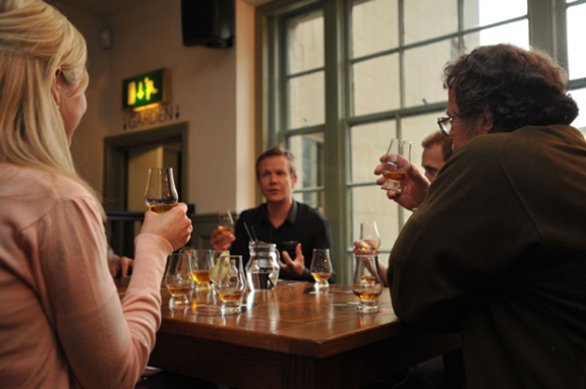 Four people sitting at a table with whisky drams