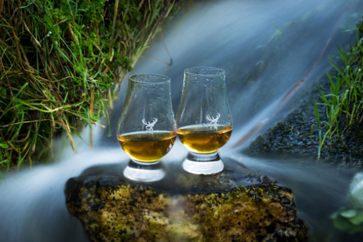 2 drams of whisky on a rock behind a water stream