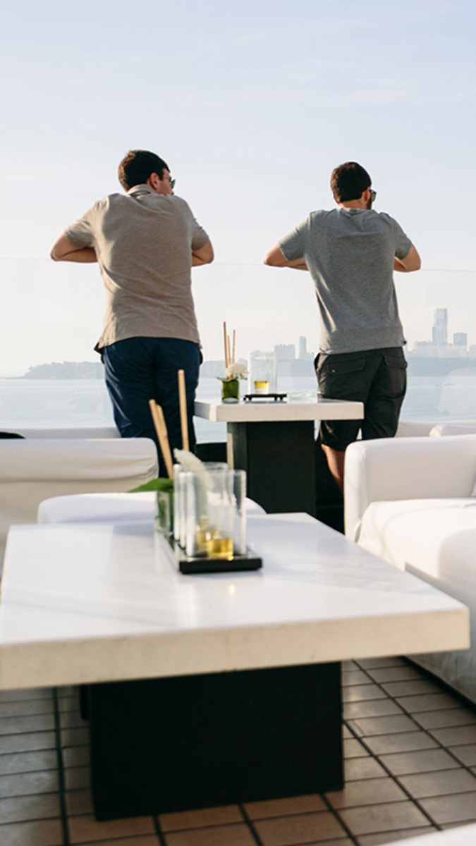 2 men on balcony looking out to sea