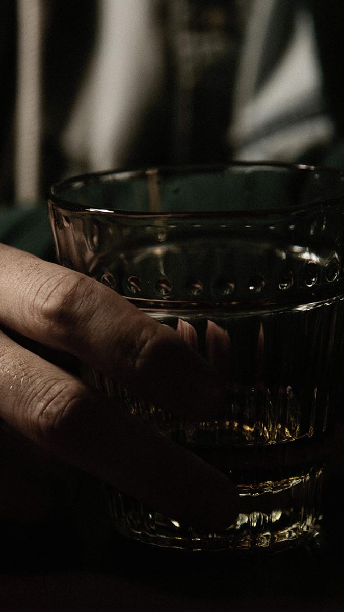 Man sitting at table holding dram of whisky