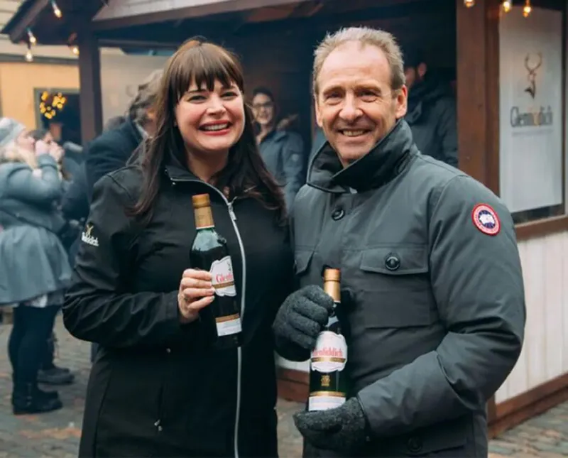 Man and woman in winter jackets holding Glenfiddicn bottles